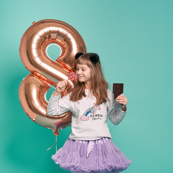 fotka dievcata s narodeninovym balonom jediaceho lizatko a cokoladu